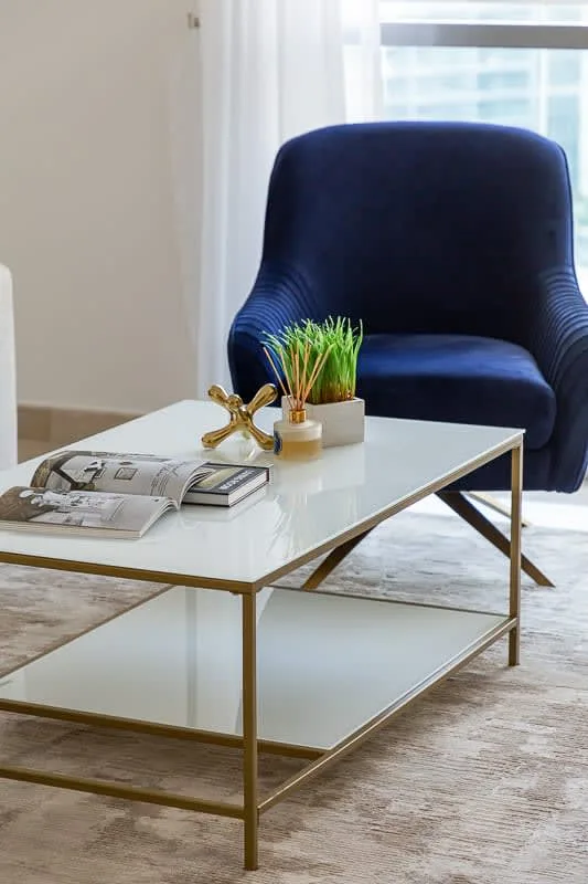Una zona de estar con un sillón oscuro y una mesa de centro blanca.