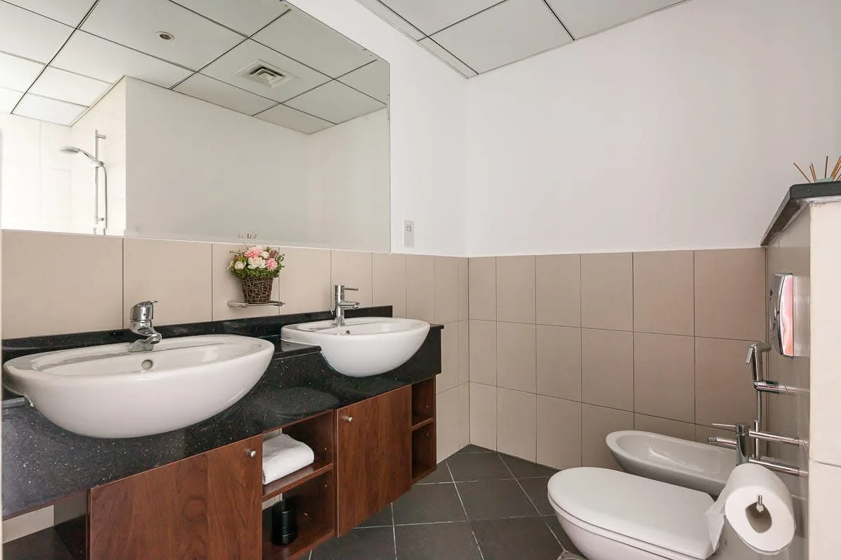 Un baño con lavabos, una pared revestida de azulejos y accesorios.