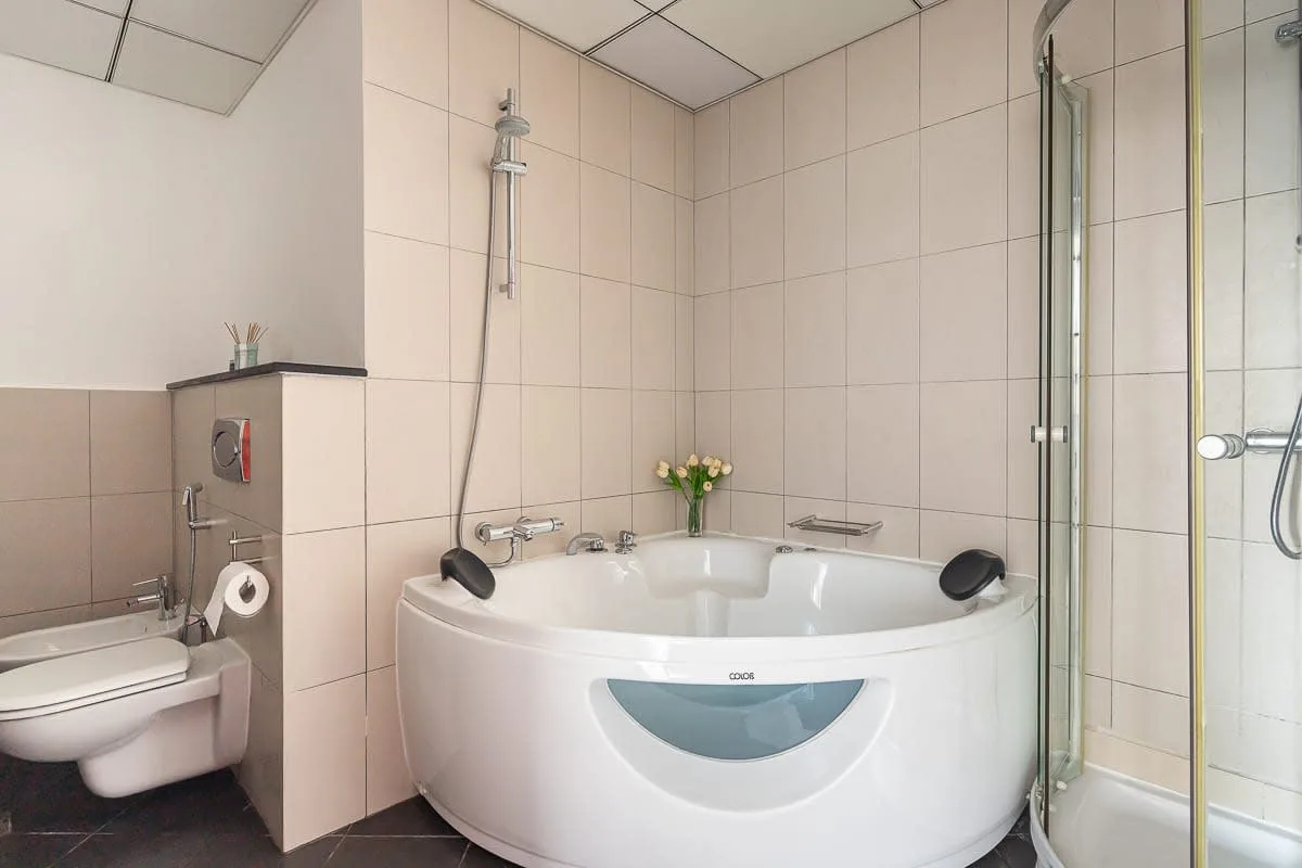 Un baño alicatado con bañera, ducha e inodoro.