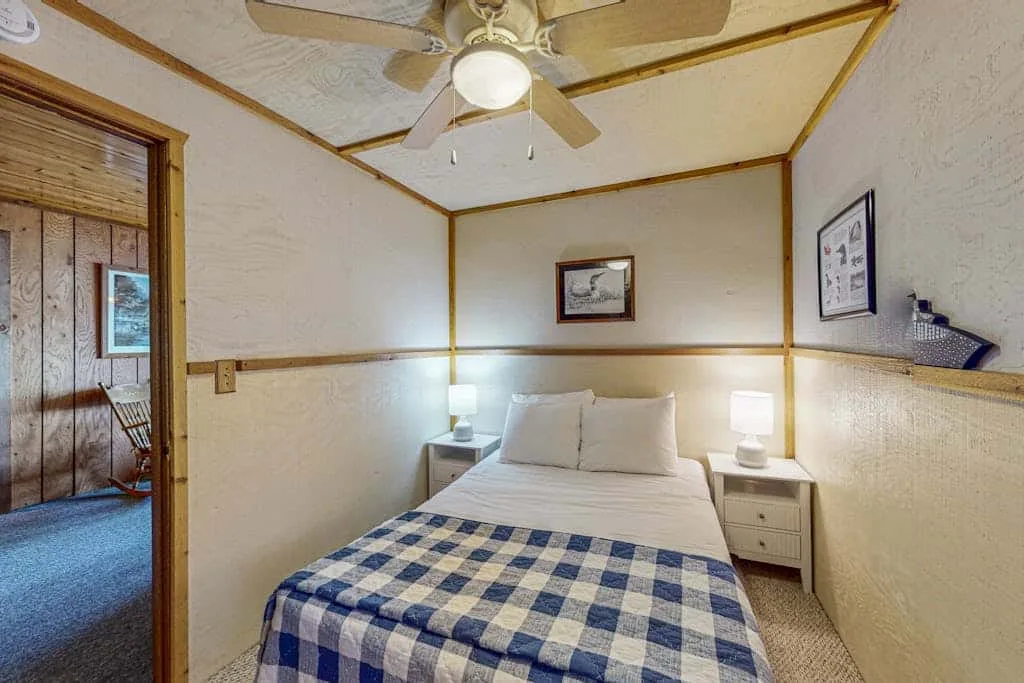 Un dormitorio con una cama tendida, mesitas de noche y un ventilador de techo.