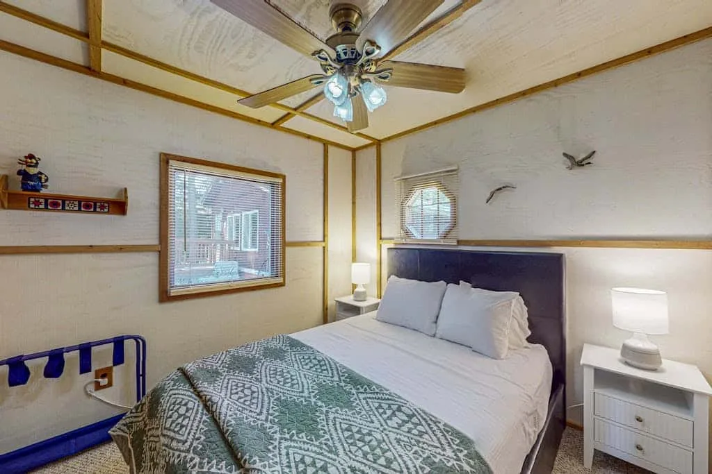 Un dormitorio con una cama, una manta estampada y una mesita de noche.