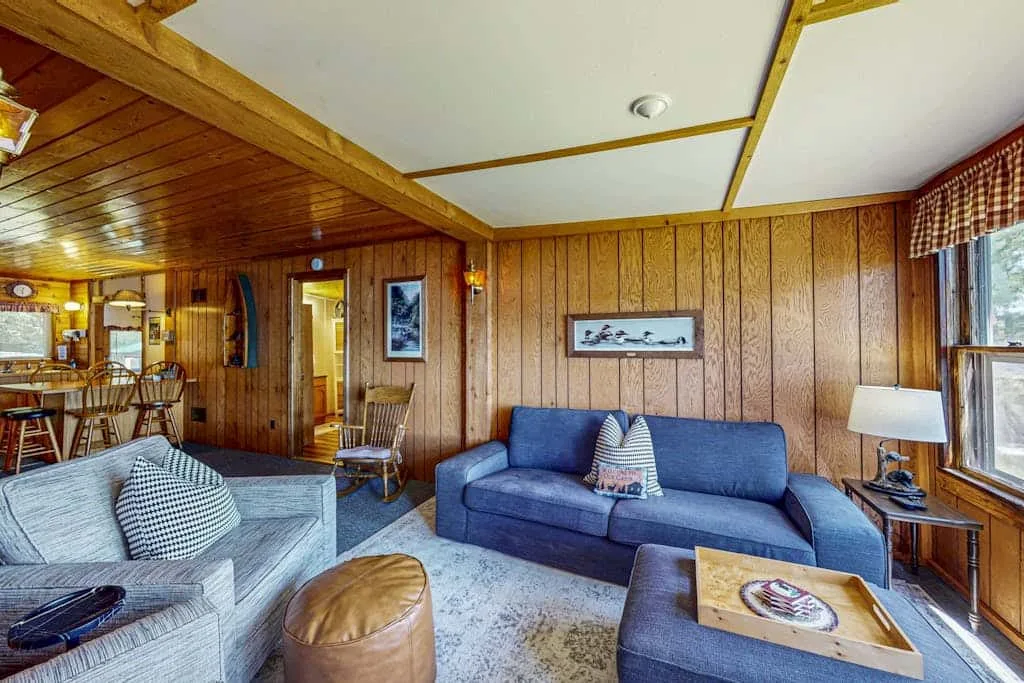 A wood-paneled living room with blue seating and a coffee table.