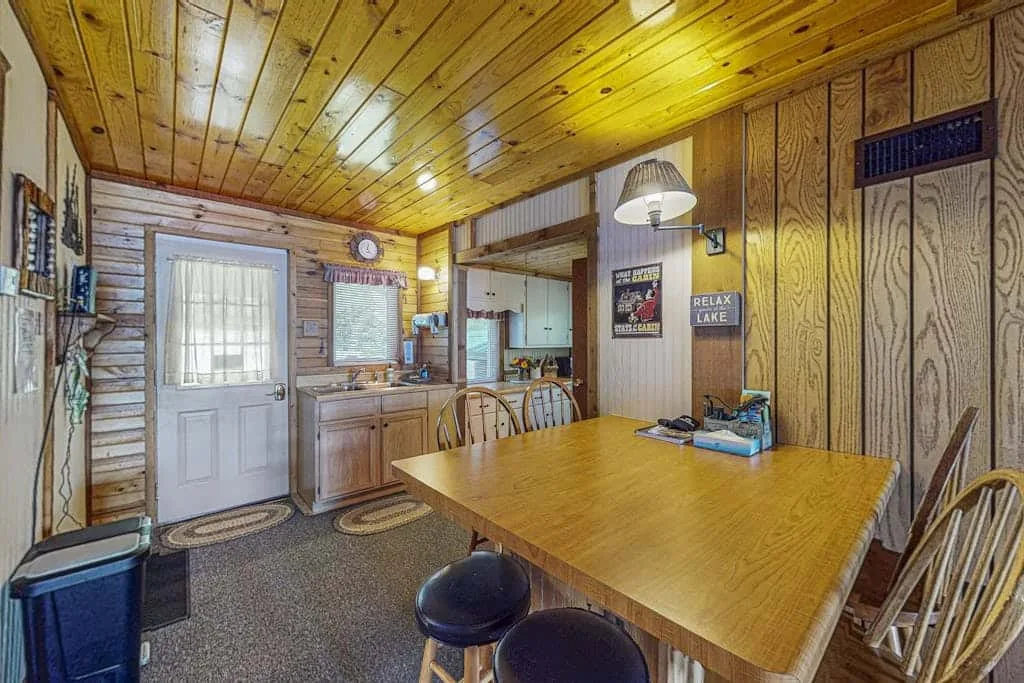 Un comedor revestido de madera con una mesa grande y sillas.