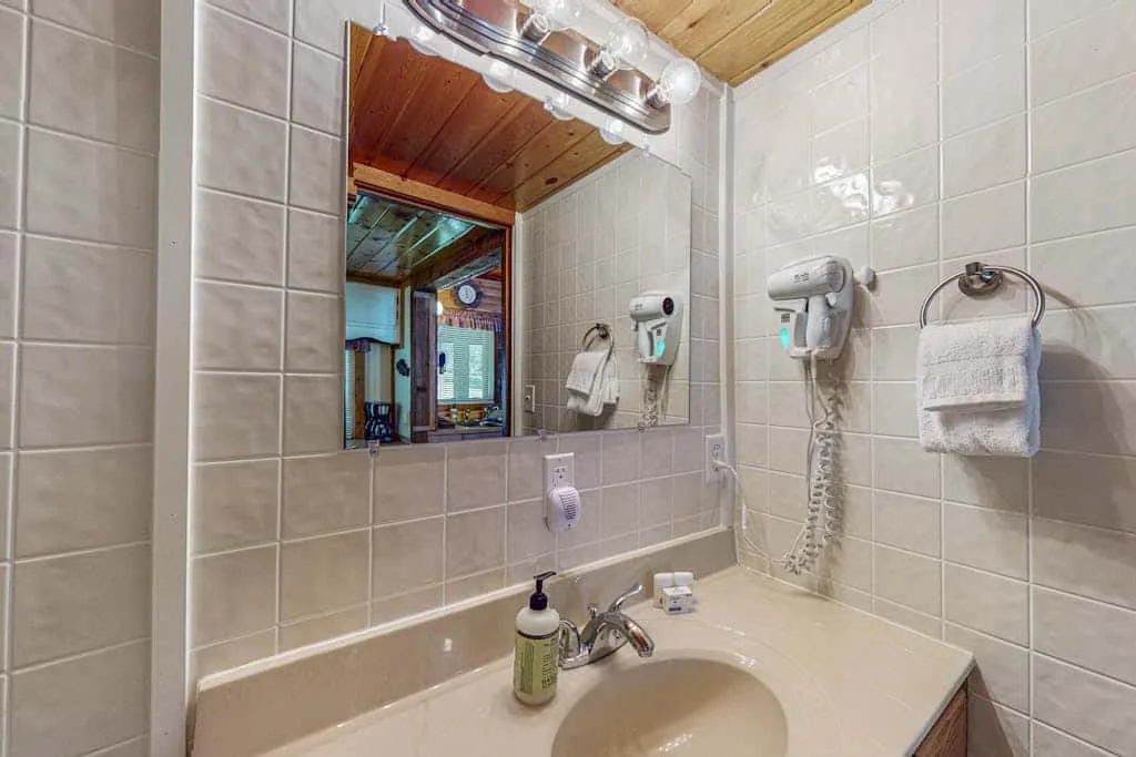 Un baño alicatado con lavabo, espejo y ducha montada en la pared.