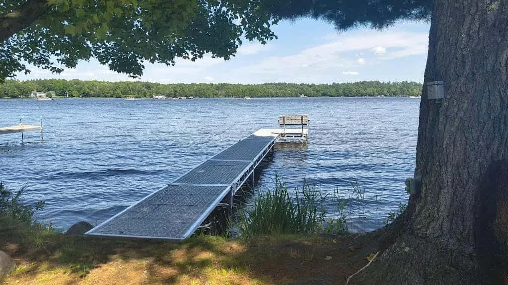 Un muelle junto al lago se adentra en el agua bajo árboles frondosos.