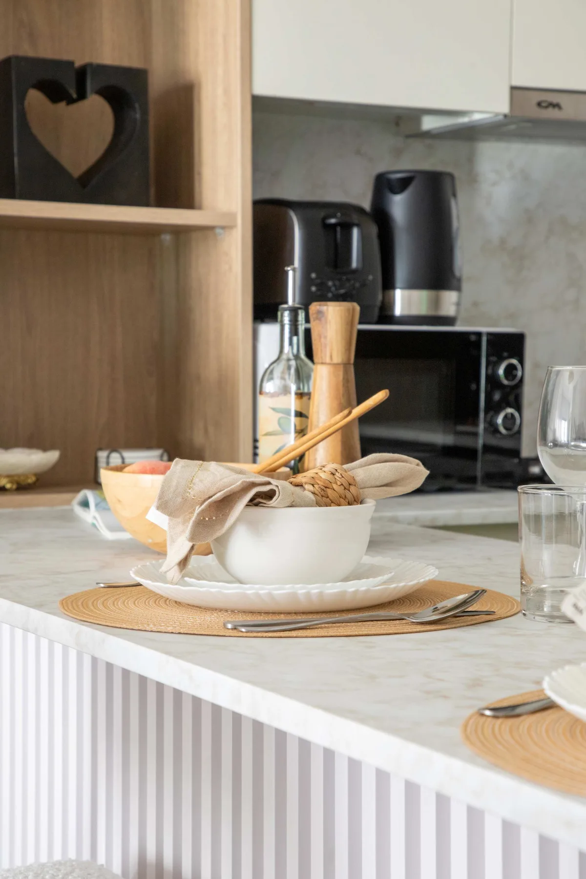 Una encimera de cocina está dispuesta con un cuenco y vajilla, con pequeños electrodomésticos detrás.
