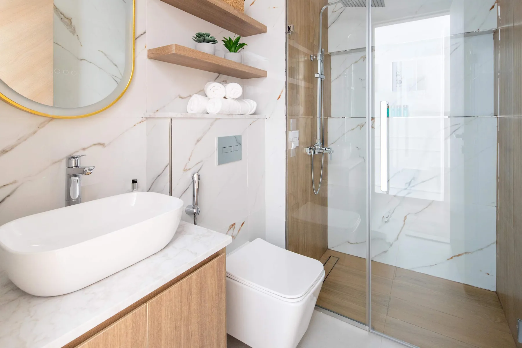 Un baño luminoso con lavabo, inodoro y ducha acristalada.