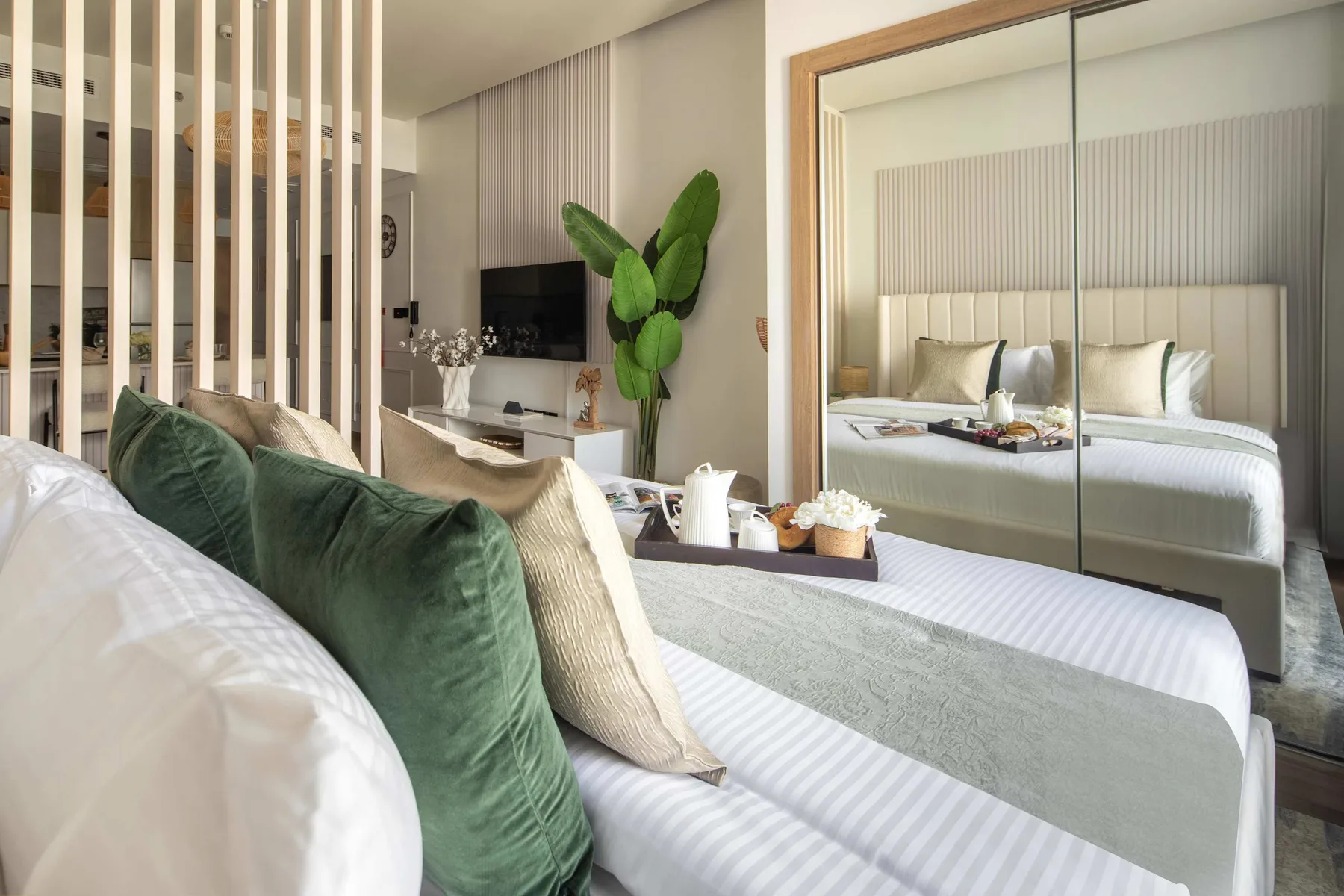 Un dormitorio con una cama, un armario con espejo y una planta en maceta.