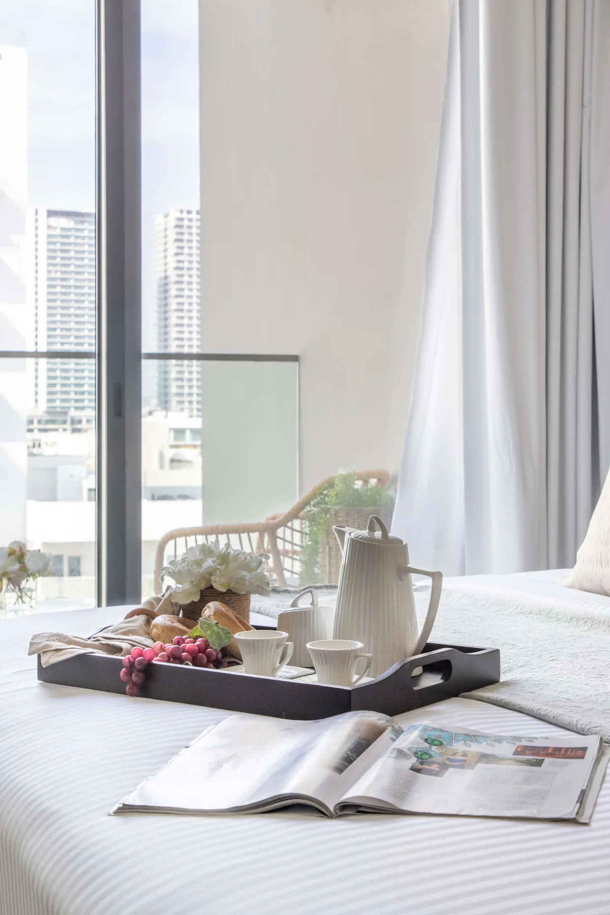 Un dormitorio luminoso con una cama, una bandeja de desayuno y una ventana grande.