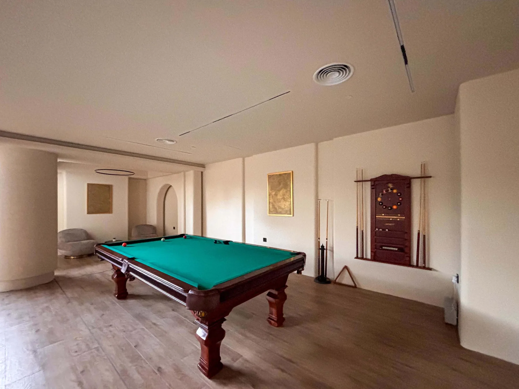 Una sala de billar tiene una mesa verde y un tablero de juego en la pared.