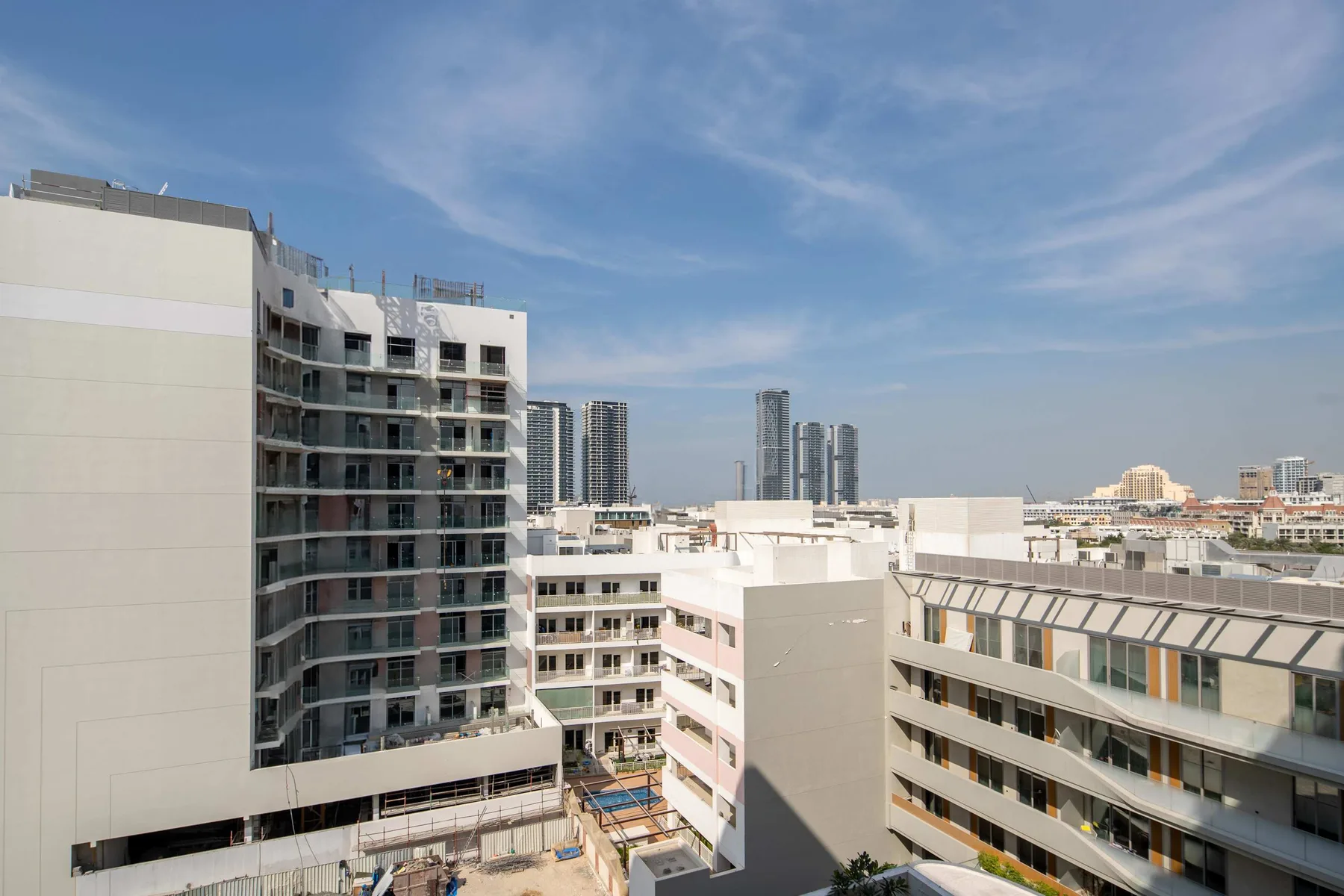 Edificios modernos con balcones se alzan bajo un cielo azul despejado.