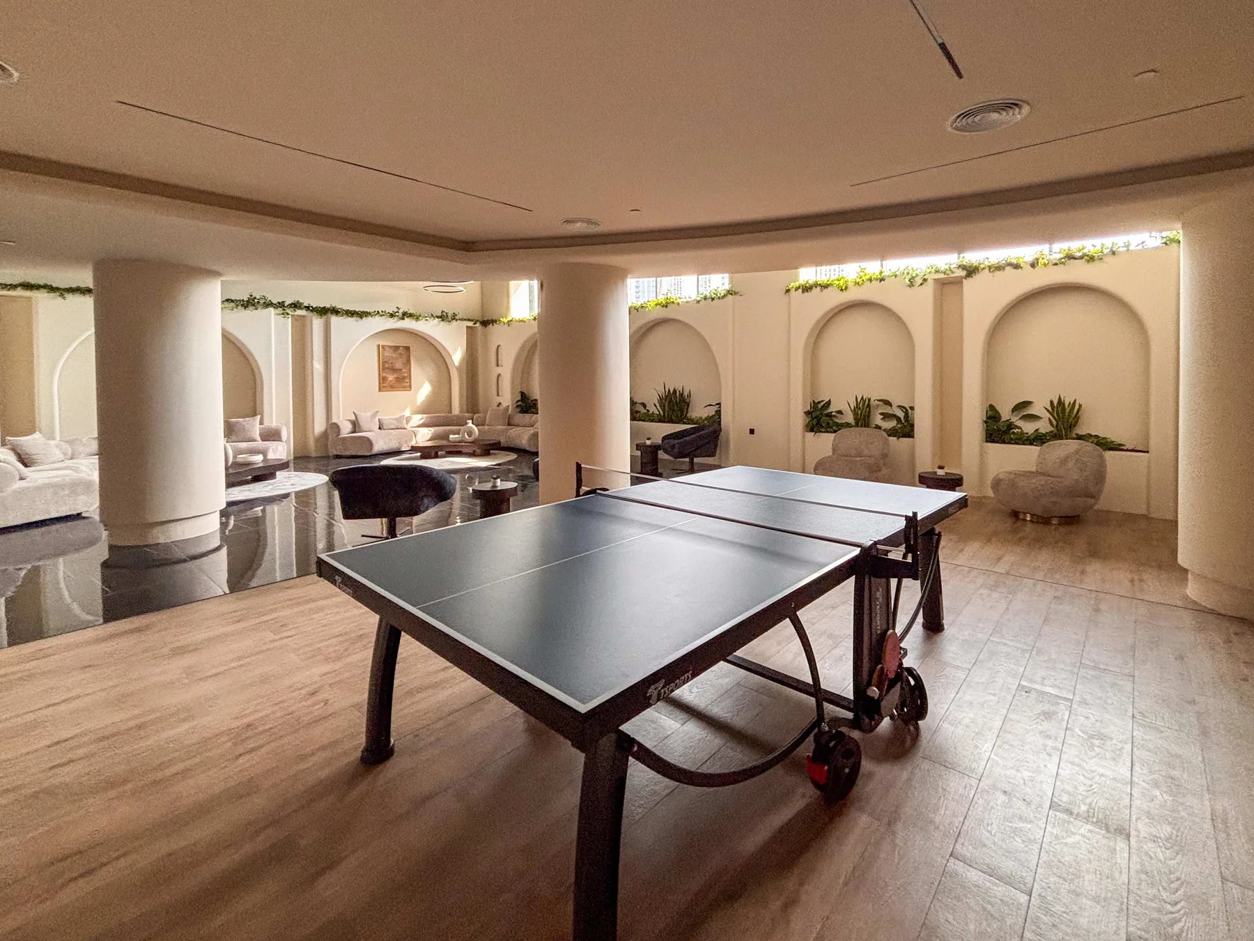 Una sala de recreación con una mesa de ping-pong y asientos al fondo.