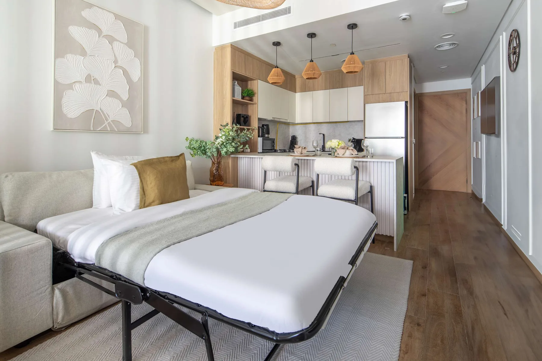 Una habitación tipo estudio con una cama frente a una cocina compacta y asientos junto a la barra.