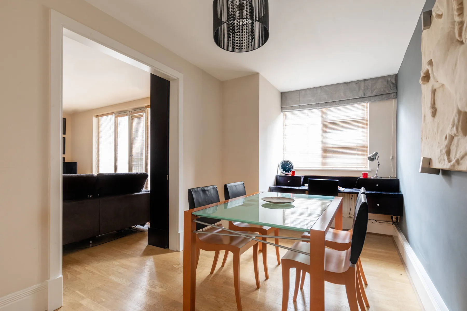 Comedor con una mesa de vidrio y sillas junto a una ventana luminosa.
