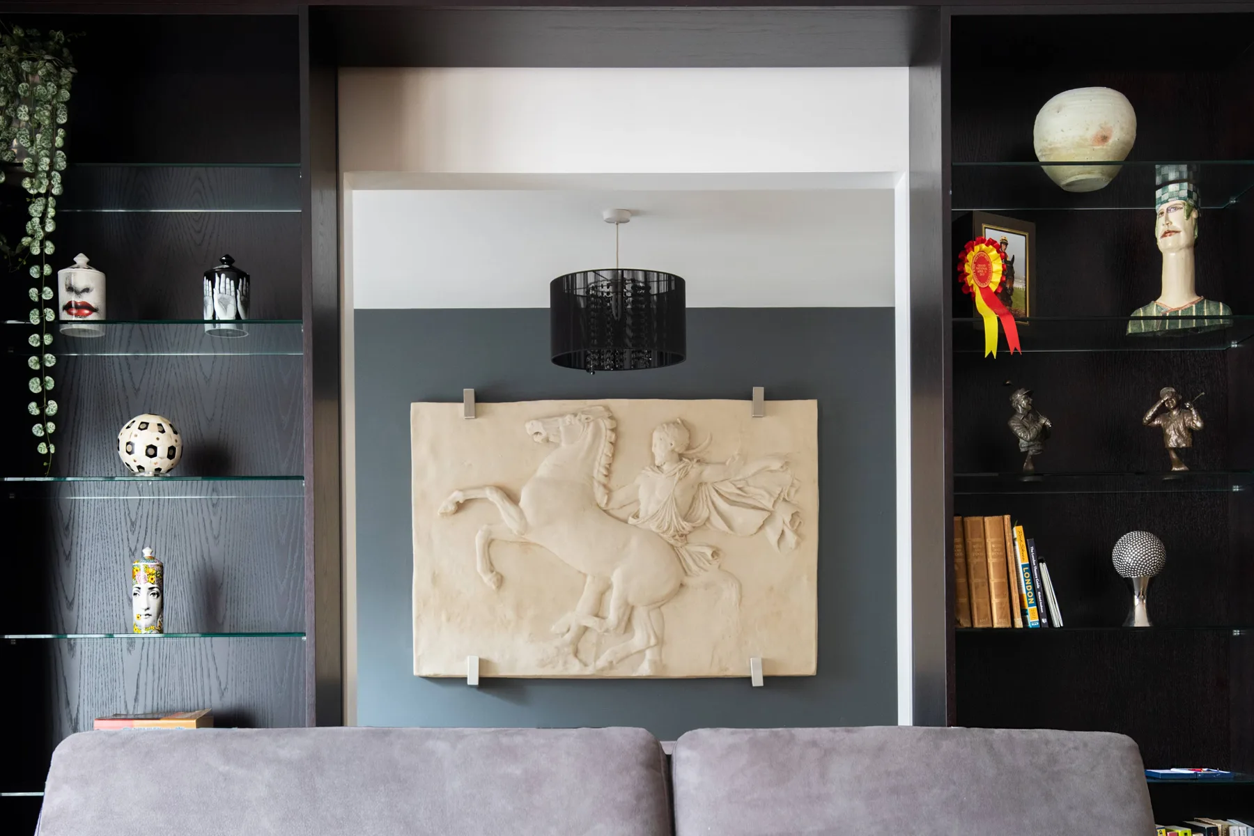 Una sala de estar con estantes oscuros de exhibición y un gran relieve decorativo en la pared.