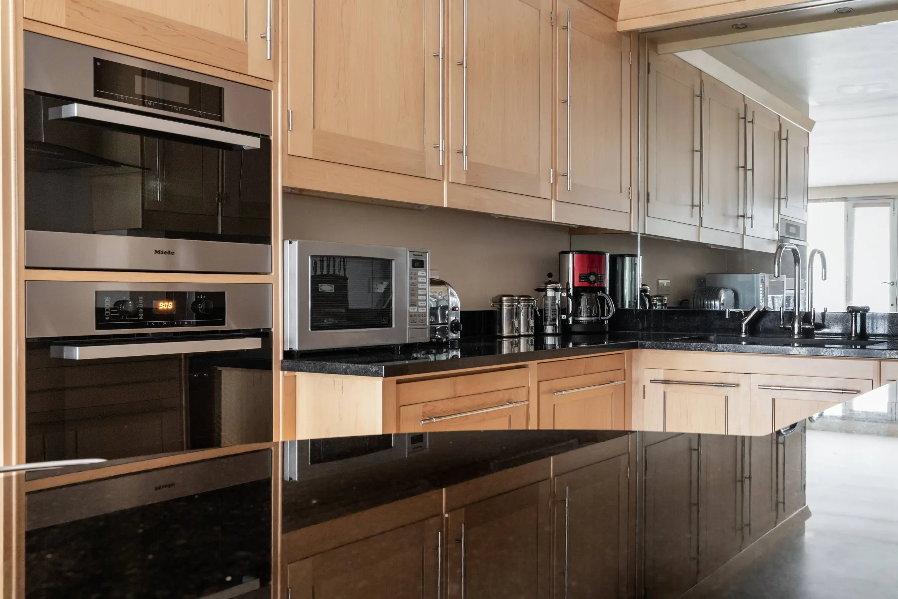 Una cocina moderna con gabinetes de madera, encimeras oscuras y electrodomésticos integrados.