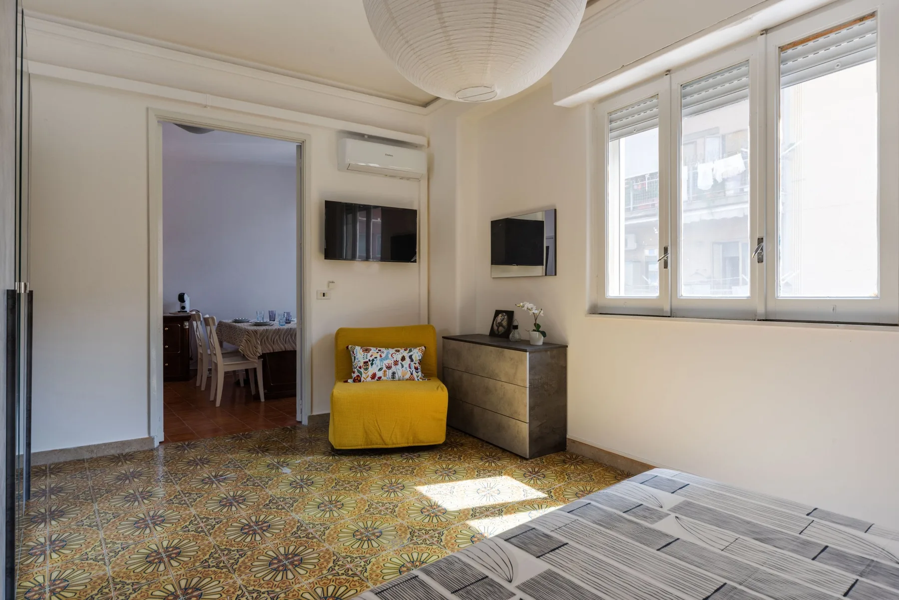 A bright sitting room with a yellow armchair beside a large window.