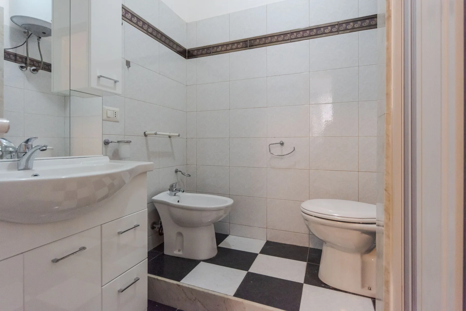 A tiled bathroom with a sink, bidet, and toilet.