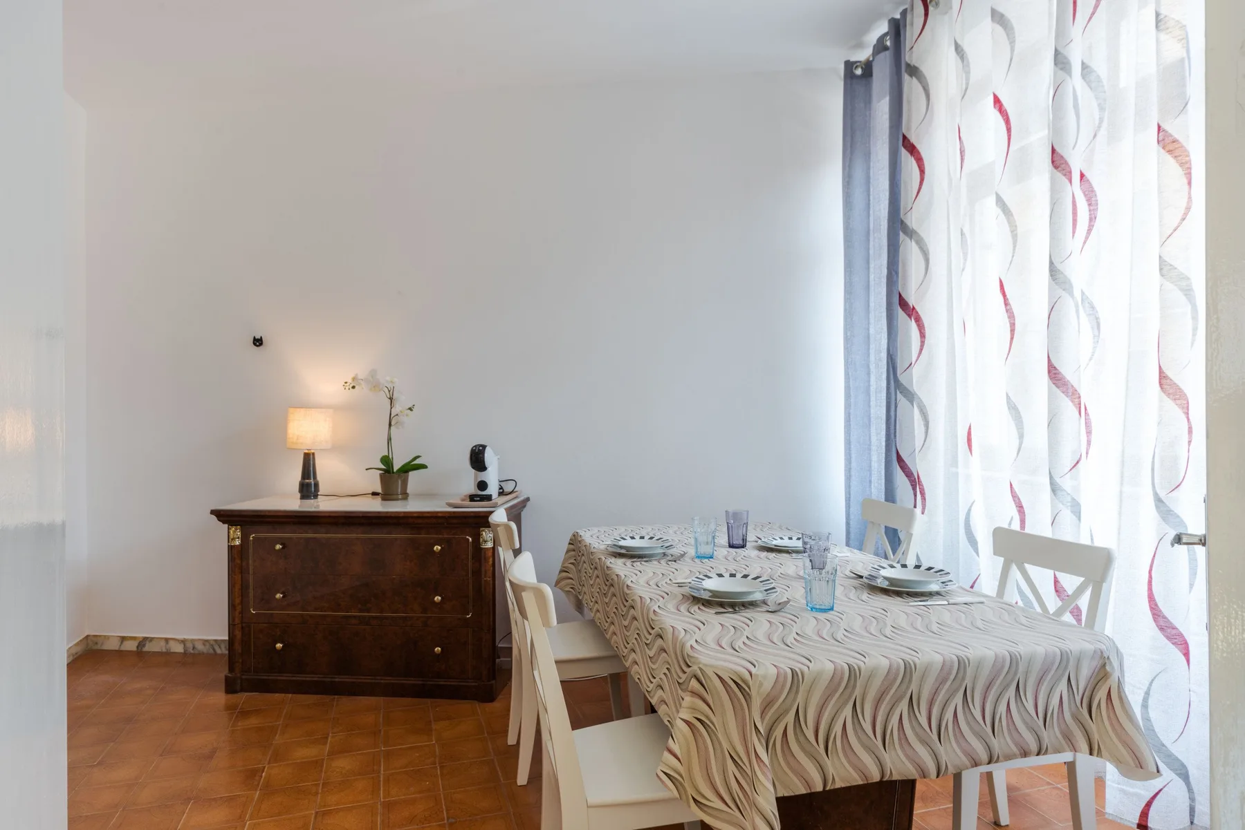 A dining area with a table set beside a curtained window.