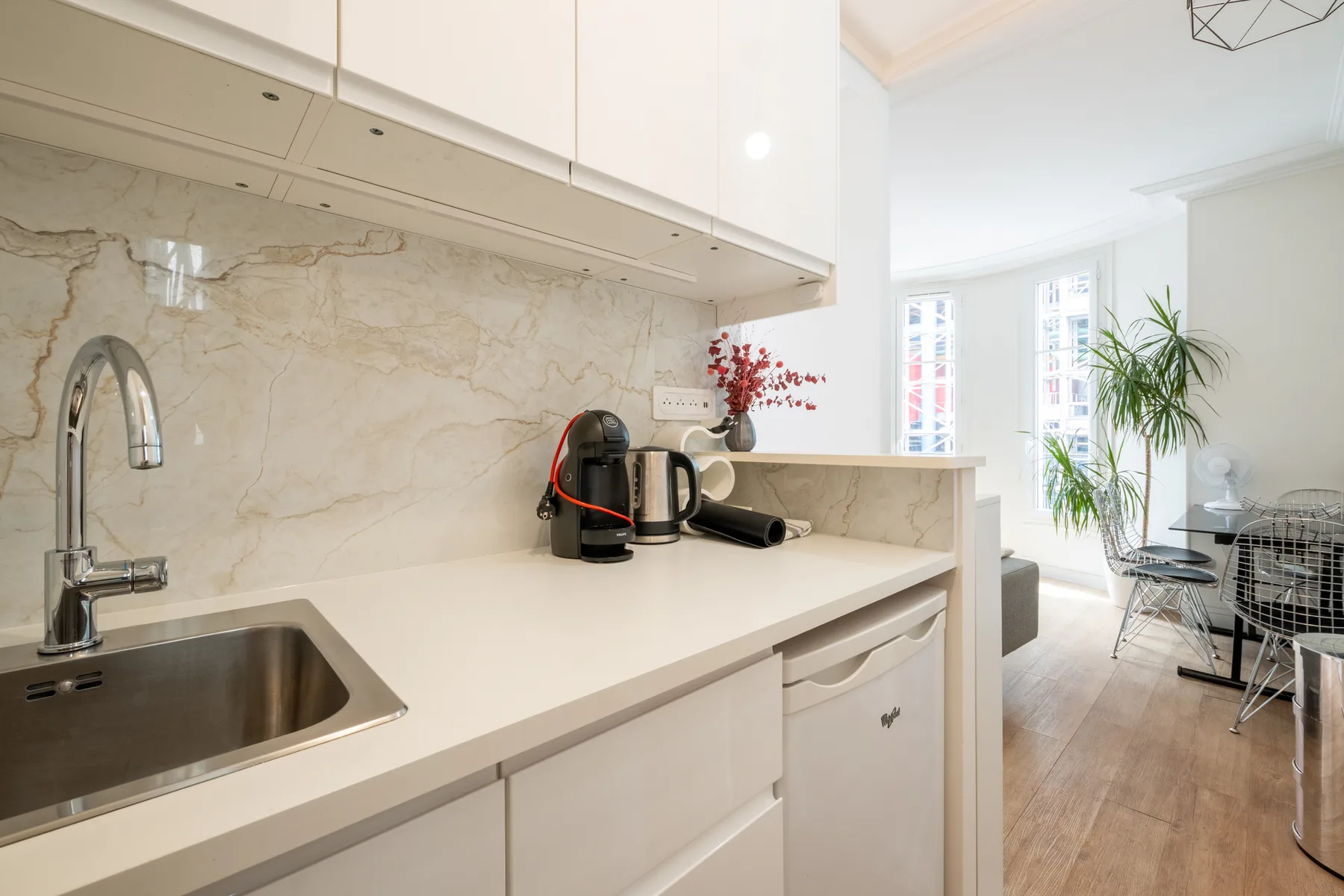 A bright kitchen opens onto a dining area with large windows.