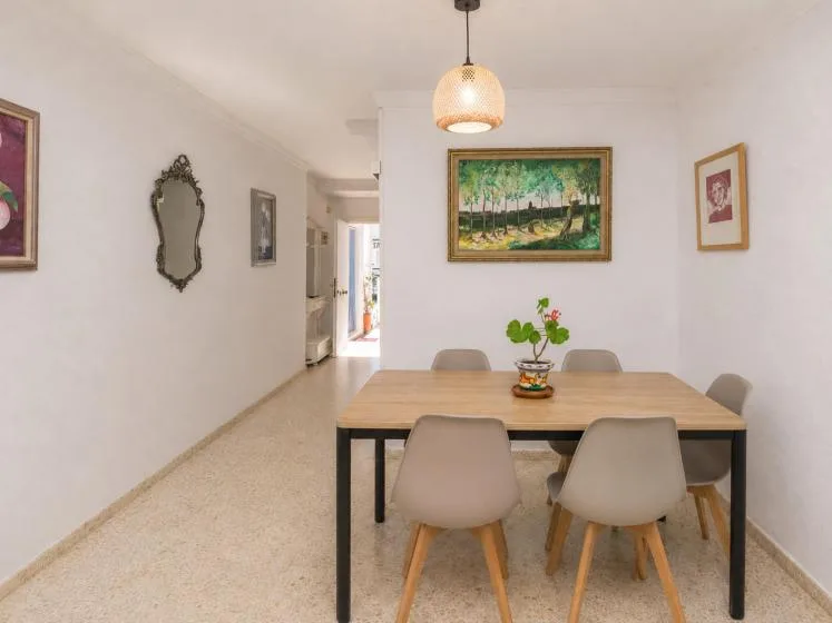 A dining area with a wooden table, chairs, and framed artwork on the walls.