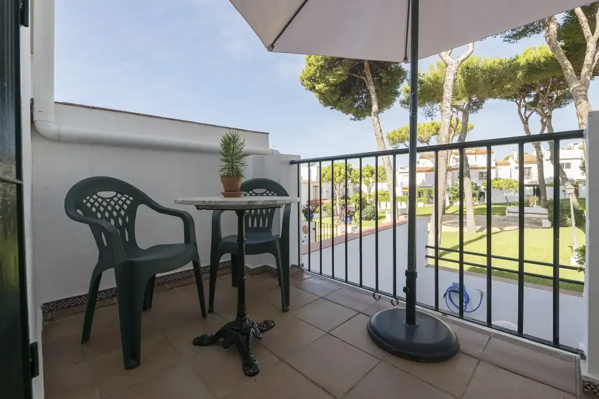 A balcony with outdoor seating overlooks a landscaped courtyard.