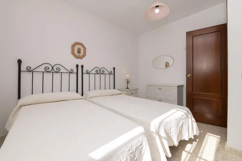 A bright bedroom with two beds and a wooden door.