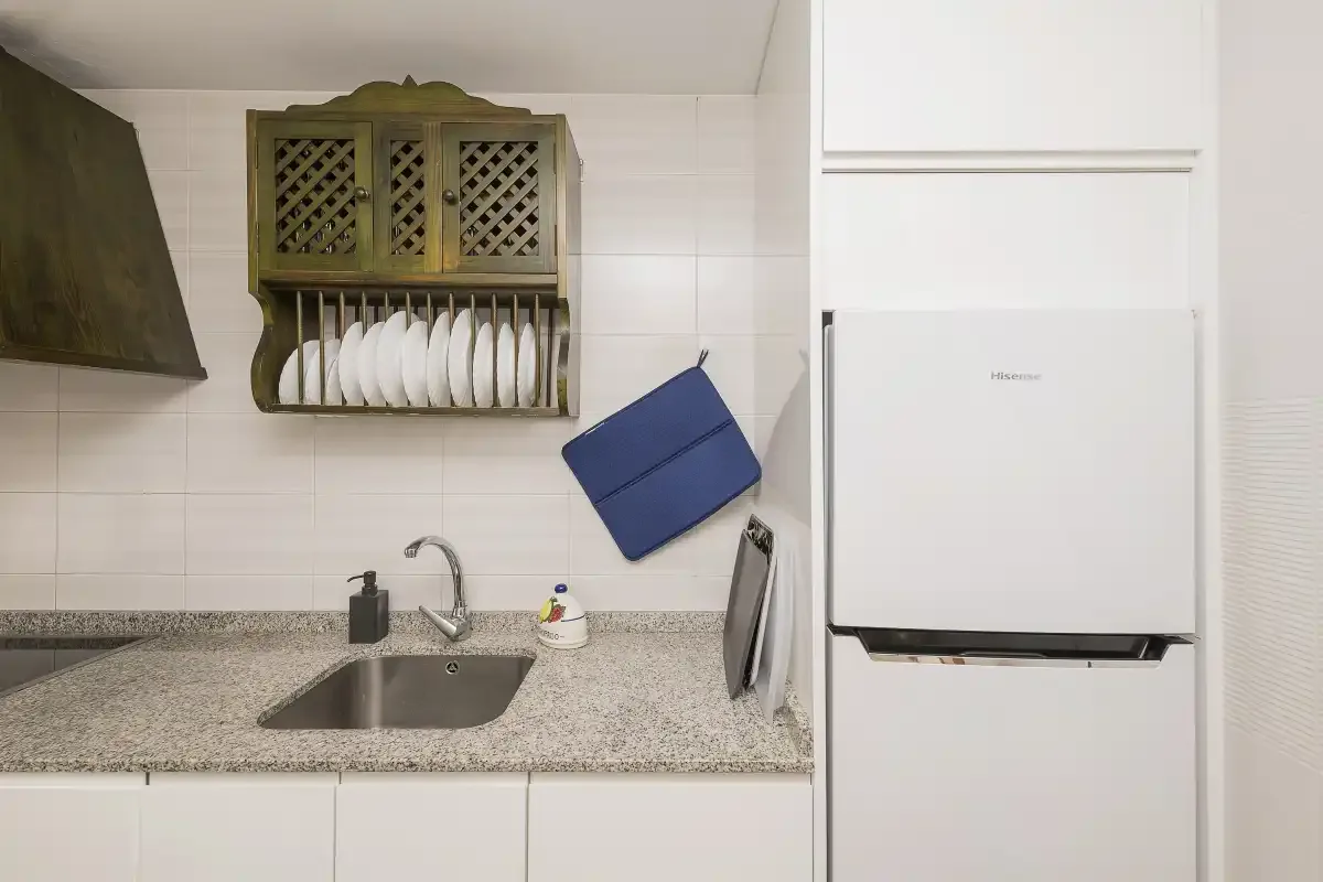 A compact kitchen with a sink, countertop, and refrigerator.