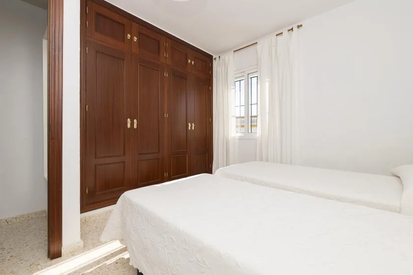 A bright bedroom with a bed beside a large wooden wardrobe.
