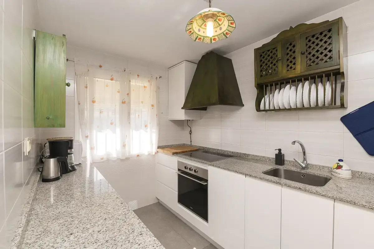 A bright kitchen with white cabinets, a countertop, and a window.