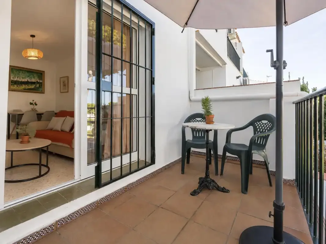 A tiled outdoor patio has a small table and seating beside an open living room.