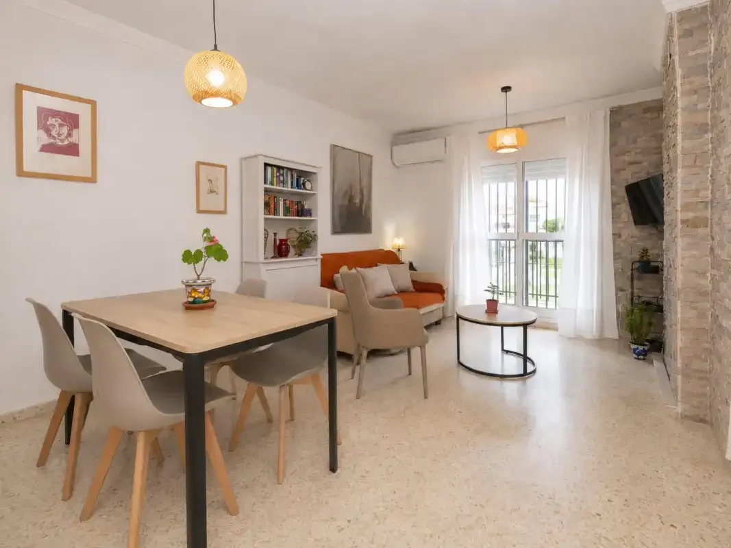 A combined living and dining area with seating beside a bright window.