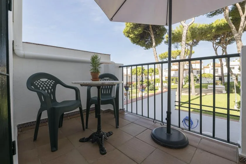 A balcony seating area with a small table and an open view of the grounds.