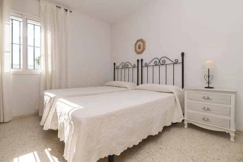 A bedroom with a bed, a window, and a bedside chest.