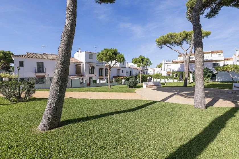 A landscaped residential courtyard with white buildings, trees, and a paved path.
