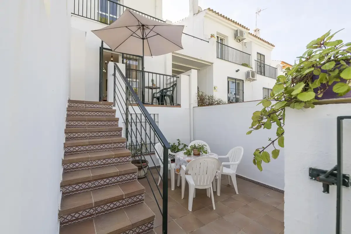An outdoor patio has a table and seating beside a staircase.