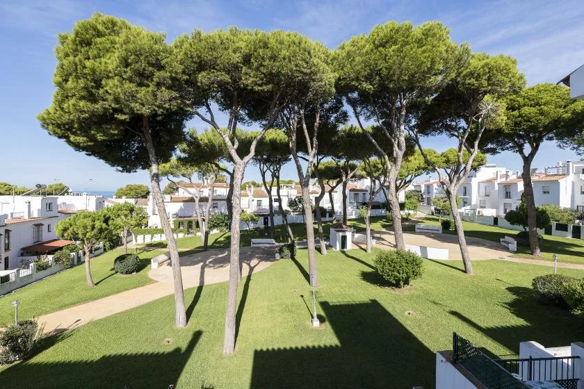 A landscaped residential courtyard with tall trees, green lawns, and paved paths.