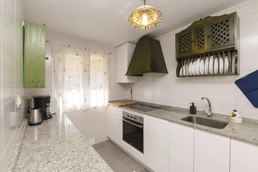 A bright kitchen with white cabinets, a countertop, and a stove.