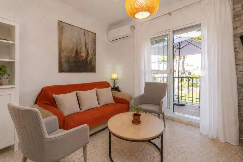 A living room with an orange sofa, armchairs, and a round coffee table.