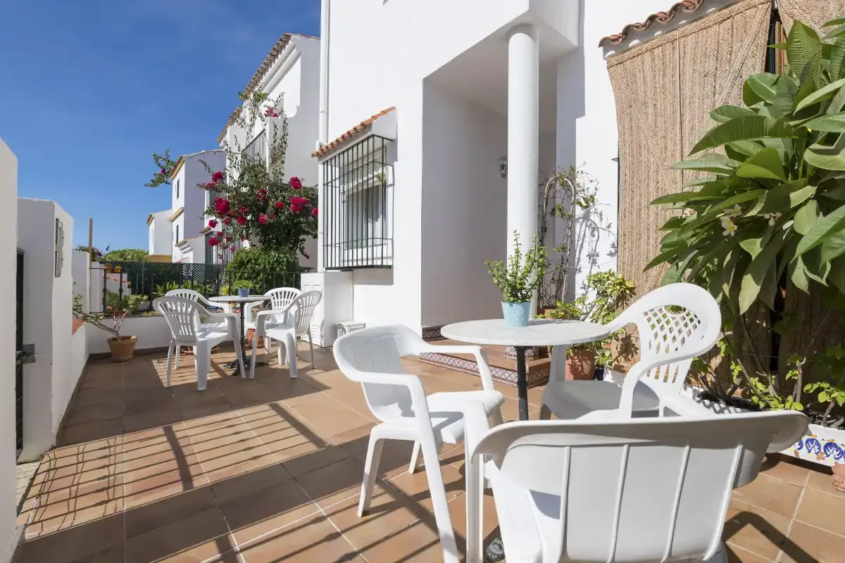 An outdoor patio with white seating and tables beside a white building.