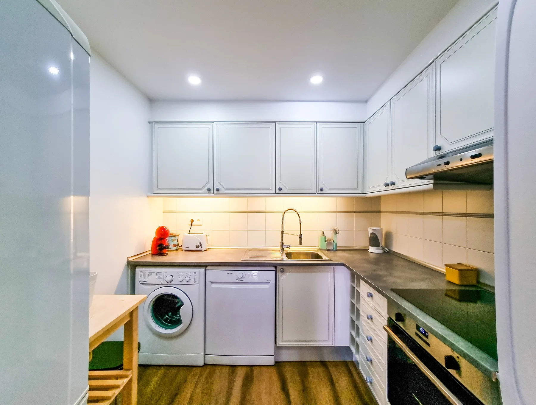 Una cocina compacta con armarios blancos y una encimera.
