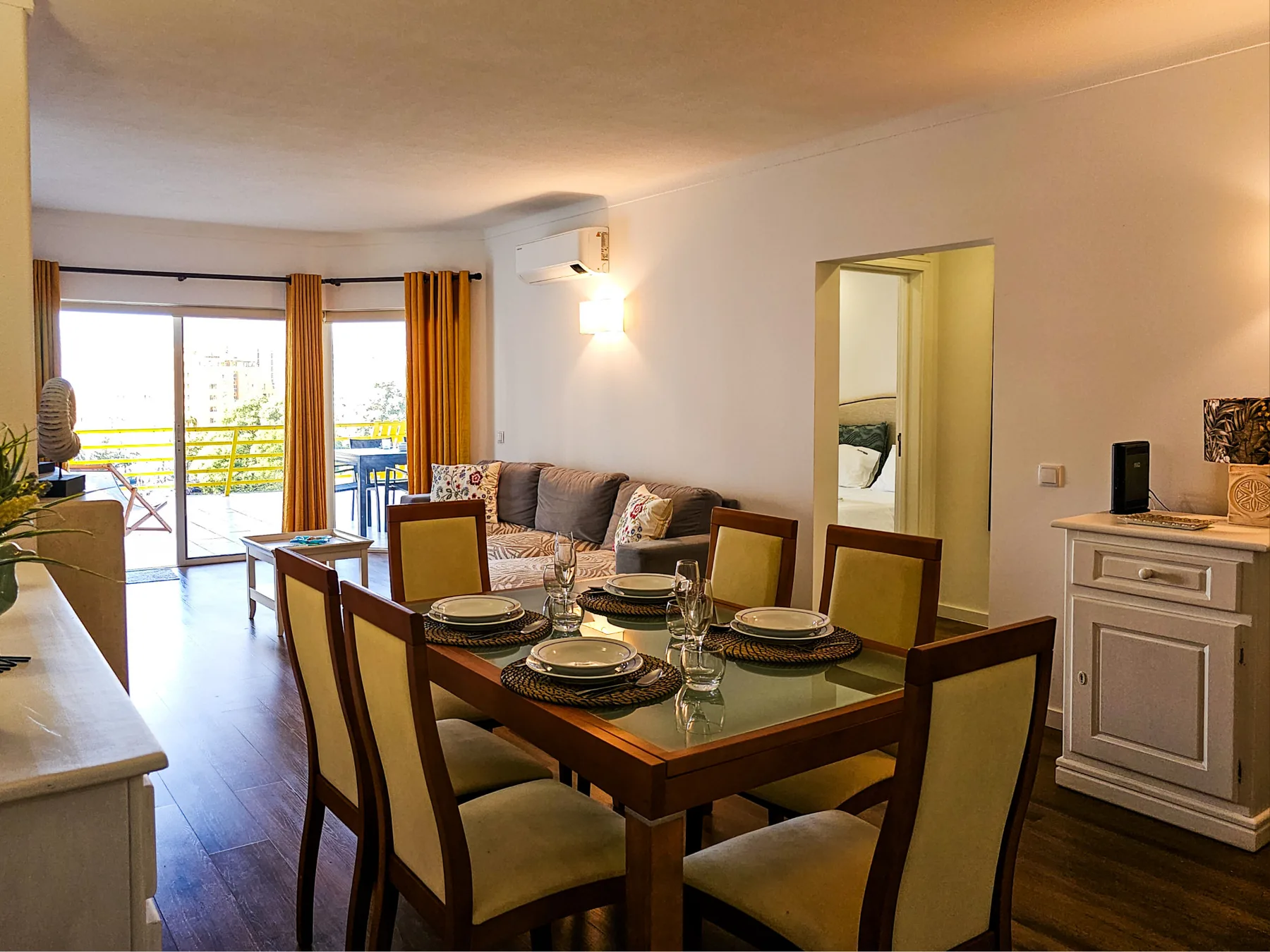 Comedor con mesa y sillas junto a una sala de estar y un balcón.