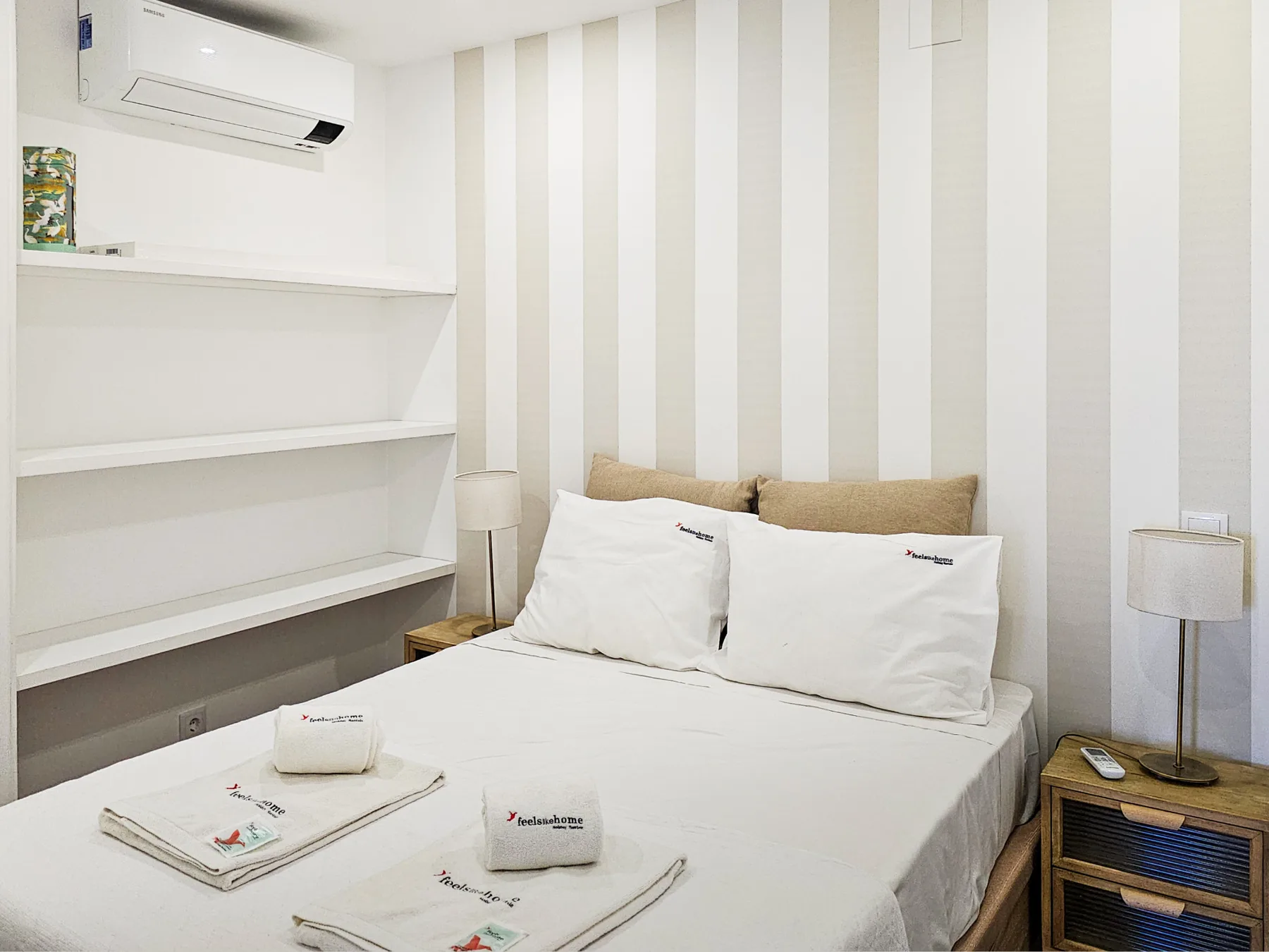 Un dormitorio luminoso con una cama bien hecha y una pared a rayas.