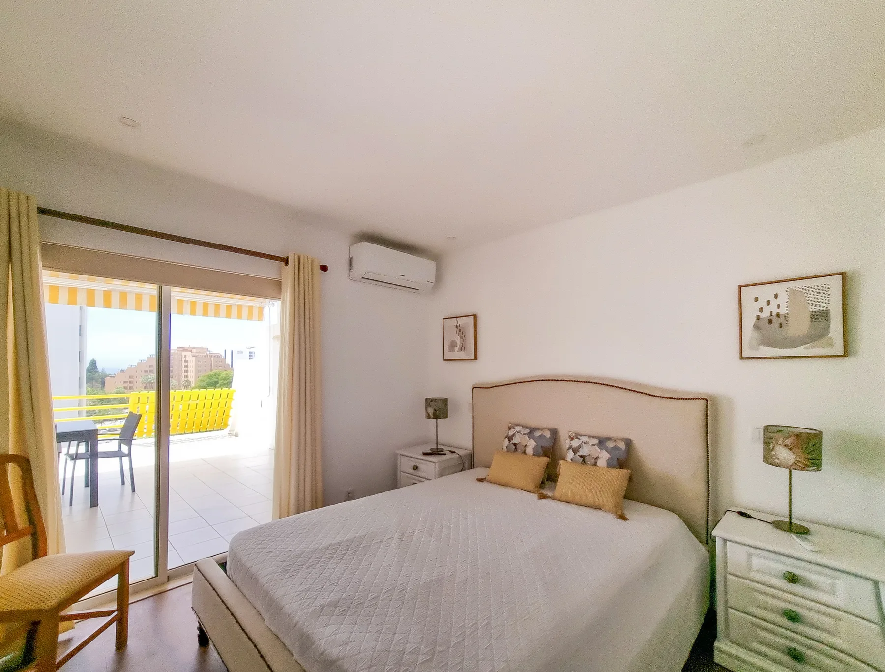 Un dormitorio luminoso con una cama doble y puertas correderas que dan a un balcón.