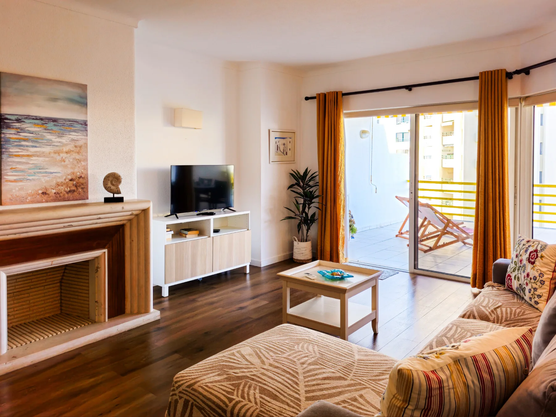 Una sala de estar con asientos, un televisor y una chimenea junto a las puertas del balcón.