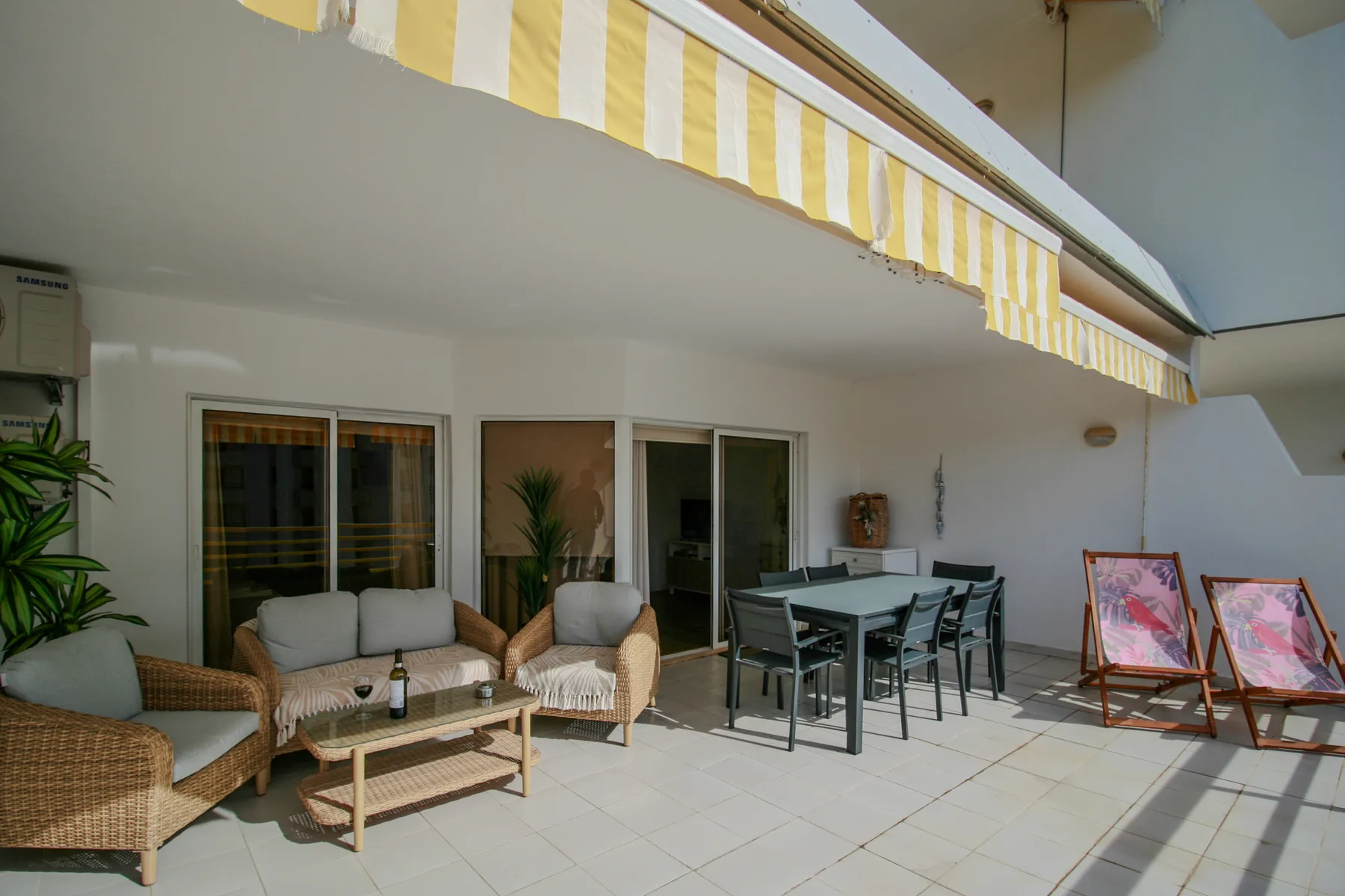 Una terraza amueblada con una mesa de comedor y un toldo a rayas.