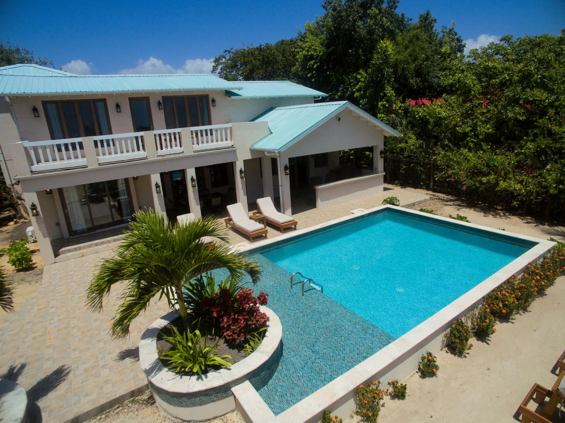 A house with a turquoise swimming pool and a small landscaped garden.
