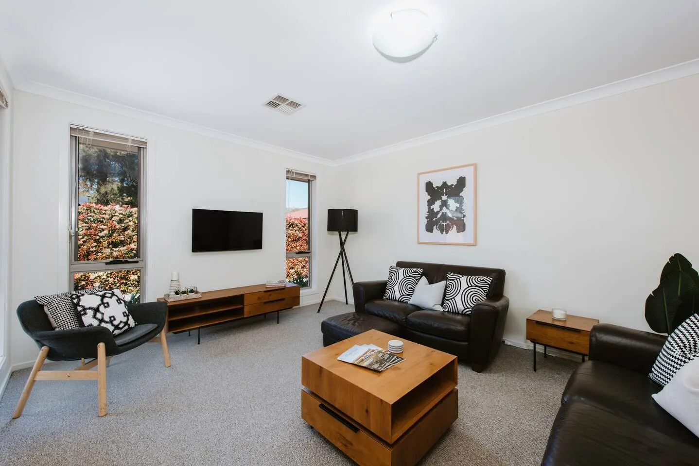 A bright living room with seating, a television, and a wooden coffee table.