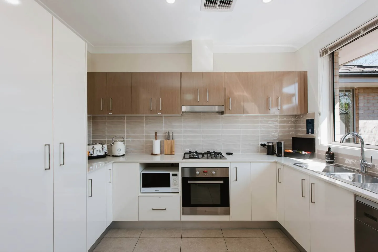 Kitchen with wood-toned upper cabinets, white lower cabinets, and a countertop stove.