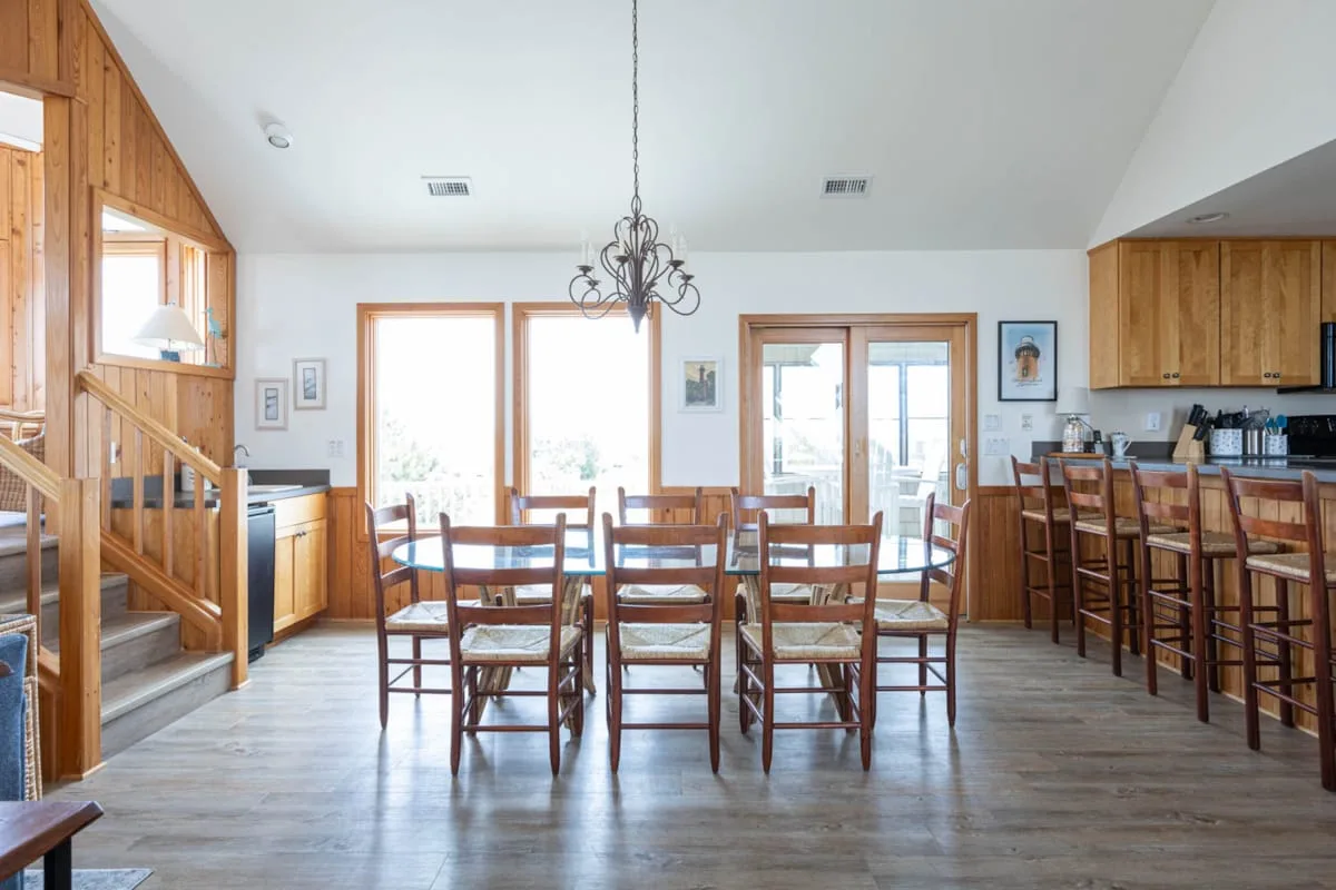 Un comedor con mesas y sillas de madera junto a una barra de cocina.